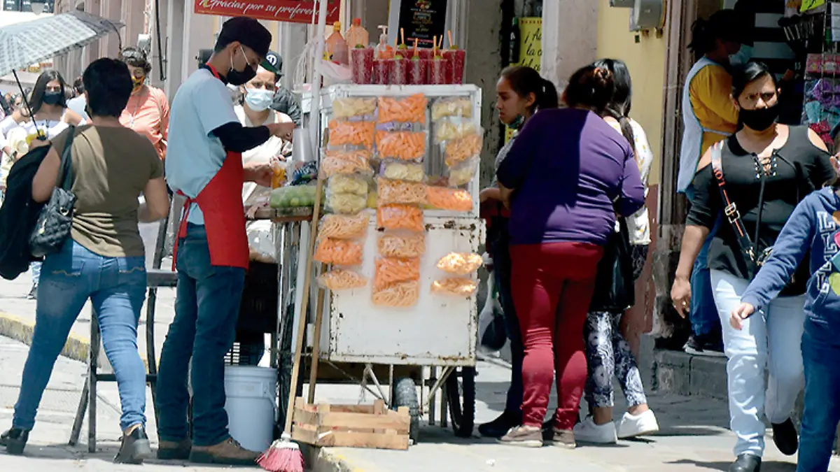 Personas en el centro de la ciudad de Zacaecas cerca de un puesto callejero